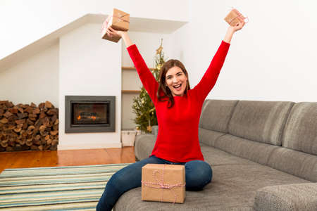 Beautiful happy woman at home holding Christmas presentsの写真素材