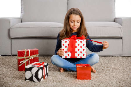 Happy little girl at home opening Christmas presentsの写真素材