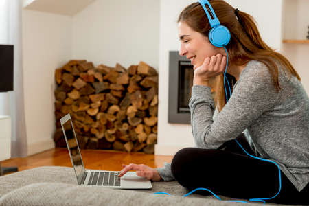 Beautiful woman working at home with a laptop while listen music