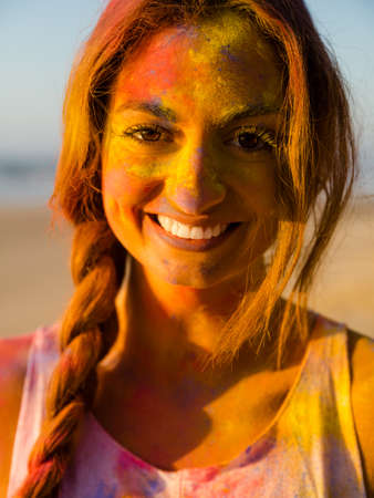 Portrait of a beautiful girl full of colored powder on the faceの写真素材