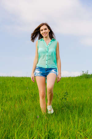 Attractive young woman walking over a green meadowの写真素材