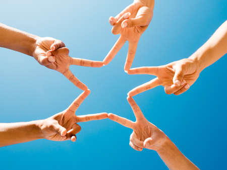 Friends making a star with fingers against the sky
