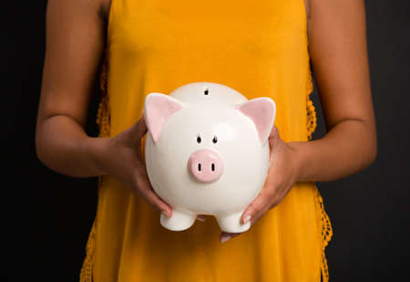Portrait of a beautiful African American woman holding a Piggybankの写真素材