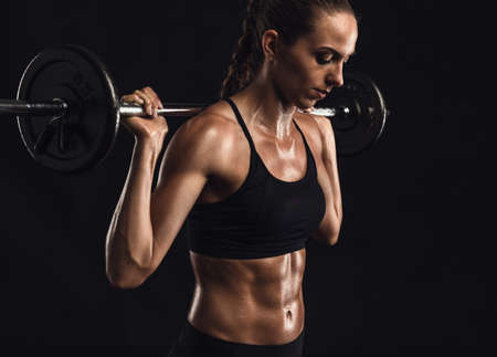 Shot of a beautiful young woman in a workout gear lifting weights