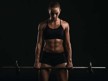 Shot of a beautiful young woman in a workout gear lifting weightsの写真素材