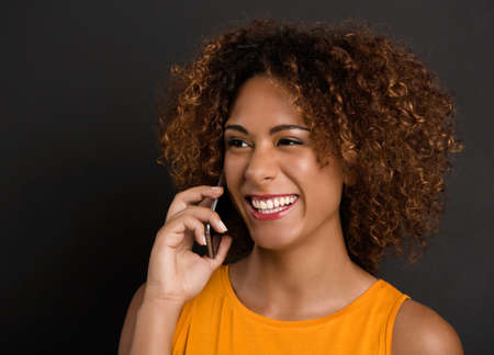 Beautiful African American woman making a phone call and laughingの写真素材