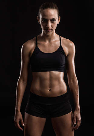Studio portrait of a sporty young woman posing against a dark backgroundの写真素材