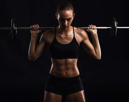 Shot of a beautiful young woman in a workout gear lifting weights
