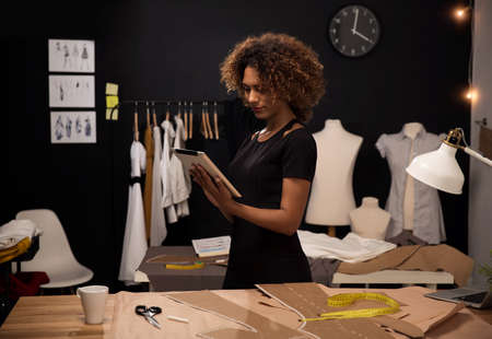 A young fashion designer on her atelier working with a tablet