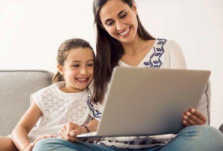 Mom teaching Daughter working with a a laptop at home