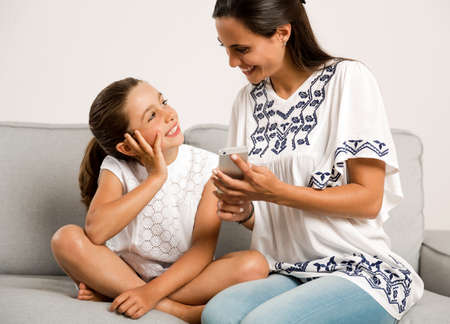 Beautiful Mom showing to her daughter something on her phone