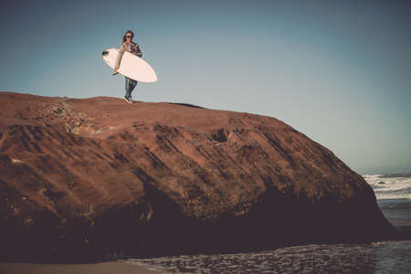 Teenage girl on the beach with her surfboard
