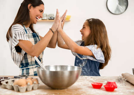 Shot of a mother and daughter having fun in the kitchen and learning to make a cakeの写真素材