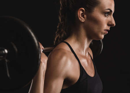 Shot of a beautiful young woman in a workout gear lifting weightsの写真素材