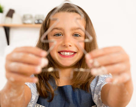Shot of a cute little girl learning to make christmas biscuitsの写真素材