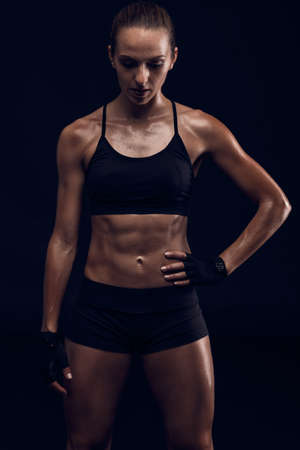 Studio portrait of a sporty young woman posing against a dark backgroundの写真素材