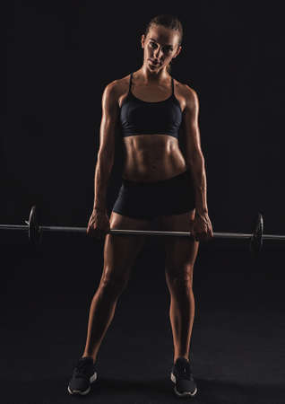 Shot of a beautiful young woman in a workout gear lifting weightsの写真素材