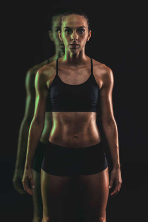 Studio portrait of a sporty young woman posing against a dark backgroundの写真素材