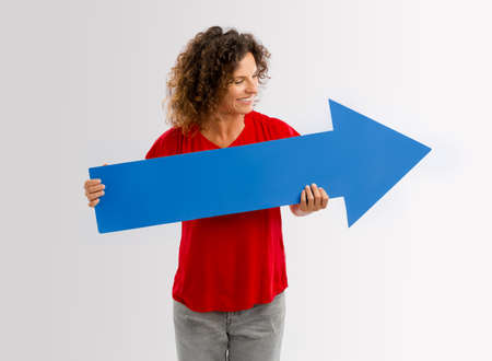 Happy mature woman holding a blue arrow