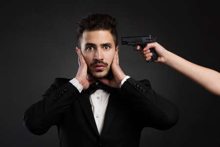 Scared young man with a weapon against his head