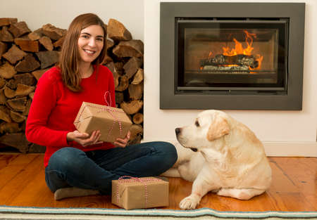 Beautiful woman at home holding some Christmas presents in the company of her dogの写真素材