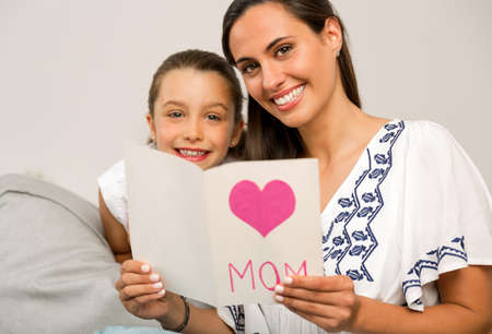 Mother receiving a greeting card on mother's day from her daughterの写真素材