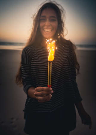 Teenage girl on the beach holding Fireworksの写真素材