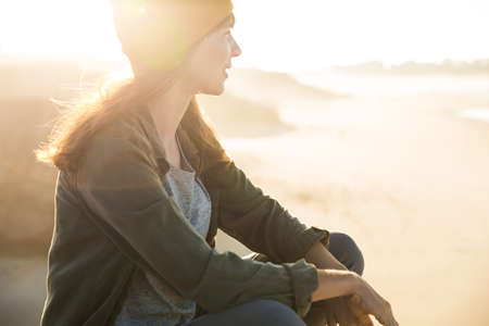 Beautiful woman sitting on a cliff over the beach