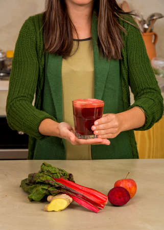 Woman holding a glass of red juice. Preparing a detox juice.