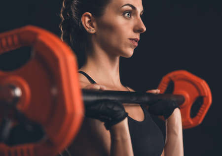 Shot of a beautiful young woman in a workout gear lifting weightsの写真素材
