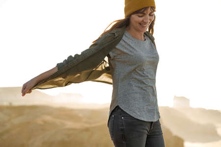Beautiful woman with a yellow cap on a cliff over the beach