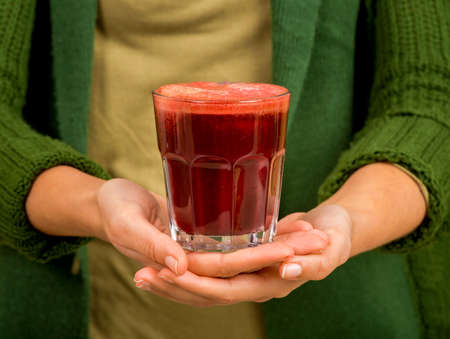 Woman holding a glass of red juice. Preparing a detox juice.の写真素材