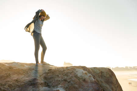 Beautiful woman with a yellow cap on a cliff over the beach