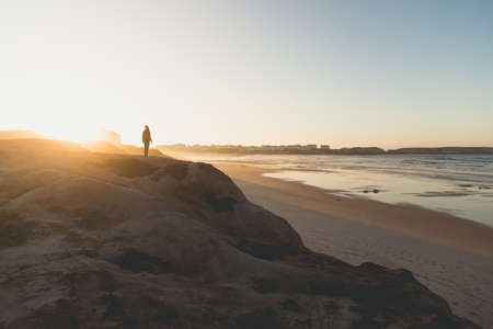 Beautiful beach with a woman walking over the cliff