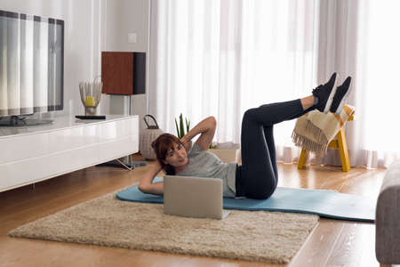 Full length shot of a woman doing exercise at homeの写真素材