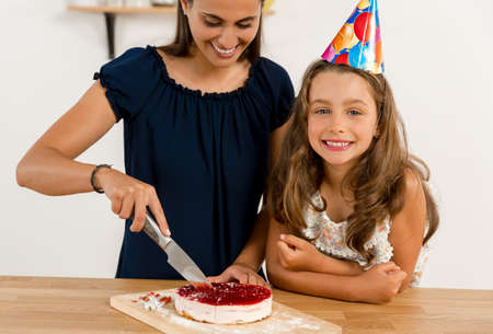Shot of a mother and daughter cuting the cutting the birthday cakeの写真素材