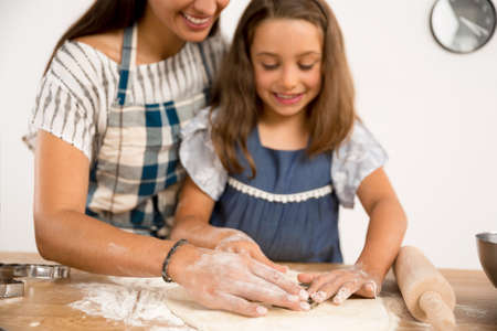 Shot of a mother and daughter having fun in the kitchen and learning to make a cakeの写真素材