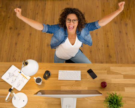 Top view of a happy businesswoman with arms open at the officeの写真素材