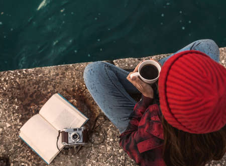 Beautiful woman enjoying her day in the lake with a mug of hot coffeeの写真素材
