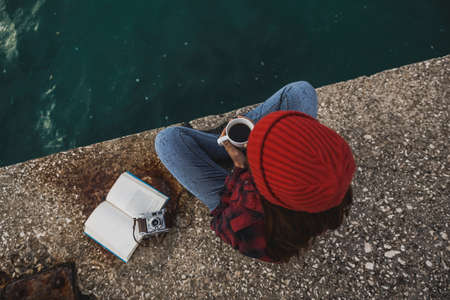 Beautiful woman enjoying her day in the lake with a mug of hot coffeeの写真素材