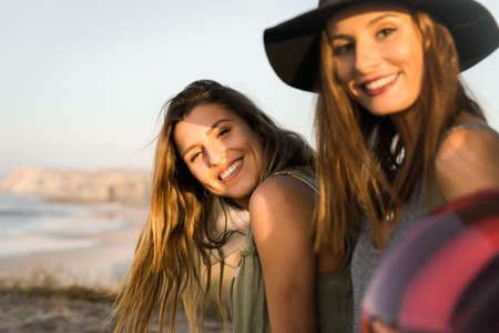 Two friends sitting in the trunk of a car near a beach and smillingの写真素材
