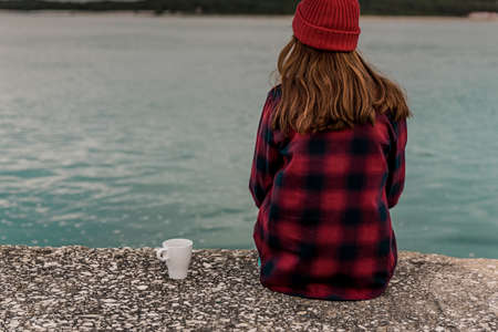 Beautiful woman enjoying her day in the lake with a mug of hot coffeeの写真素材