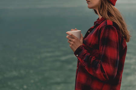 Beautiful woman enjoying her day in the lake with a mug of hot coffeeの写真素材