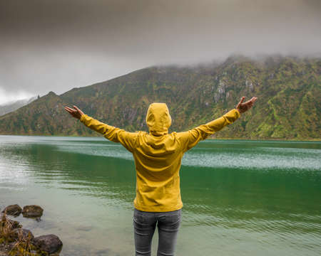 Woman with arms raisaed feeling the nature and enjoying the lake viewの写真素材