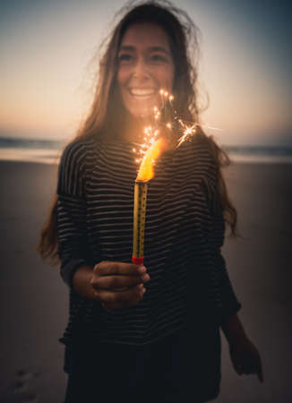 Teenage girl on the beach holding Fireworks の写真素材
