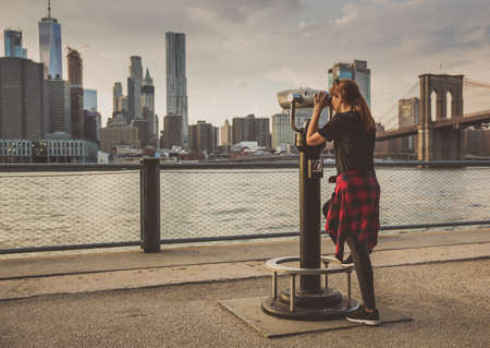 Women looking to New York through a telescopeの写真素材