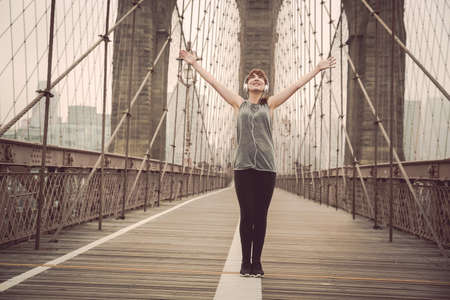 Woman on the Brooklyn bridge with arms raisedの写真素材