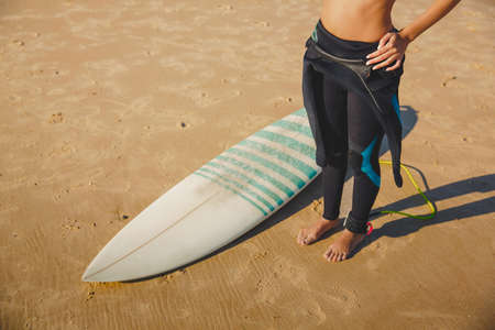 Top view of a surfer girl on the beach with her surfboardの写真素材