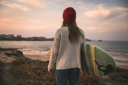 Surfer girl near the coastline with her surfboard searching for wavesの写真素材