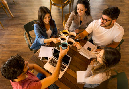 Group of friends studying together and making a toast with coffeeの写真素材